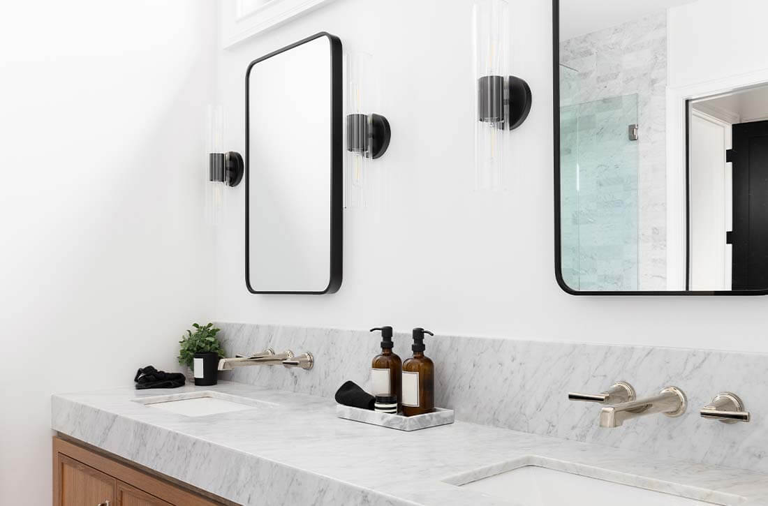 Minimalist bathroom vanity with clear glass tube sconces.