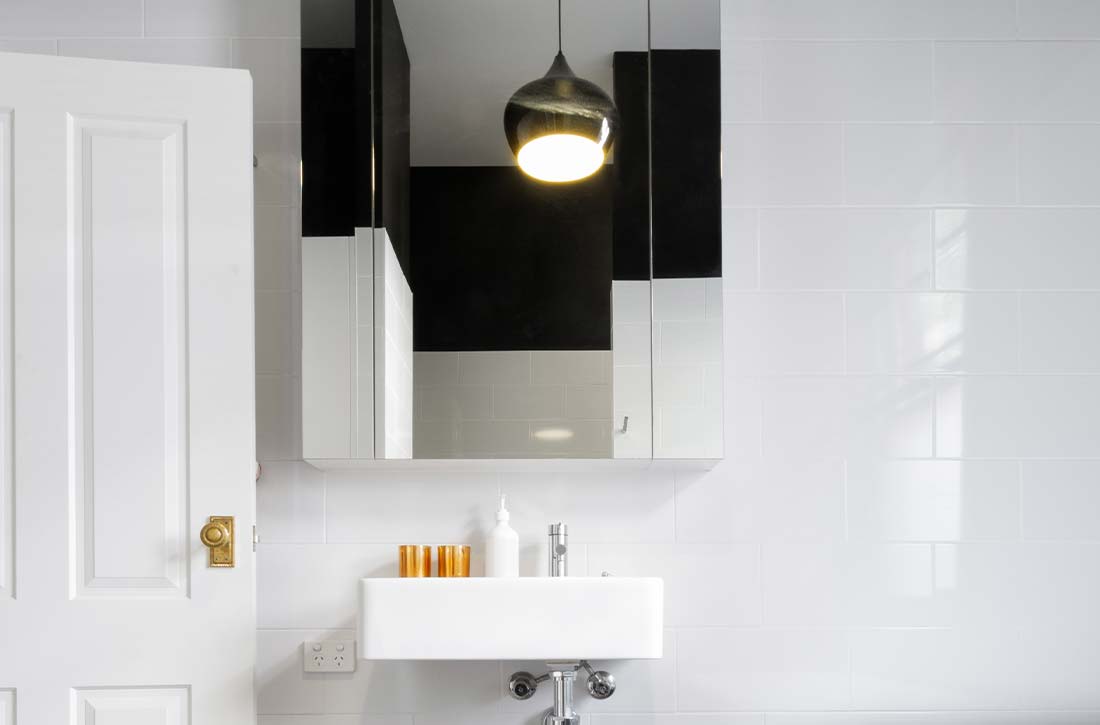 Industrial-style bathroom with statement cage pendant over vanity.