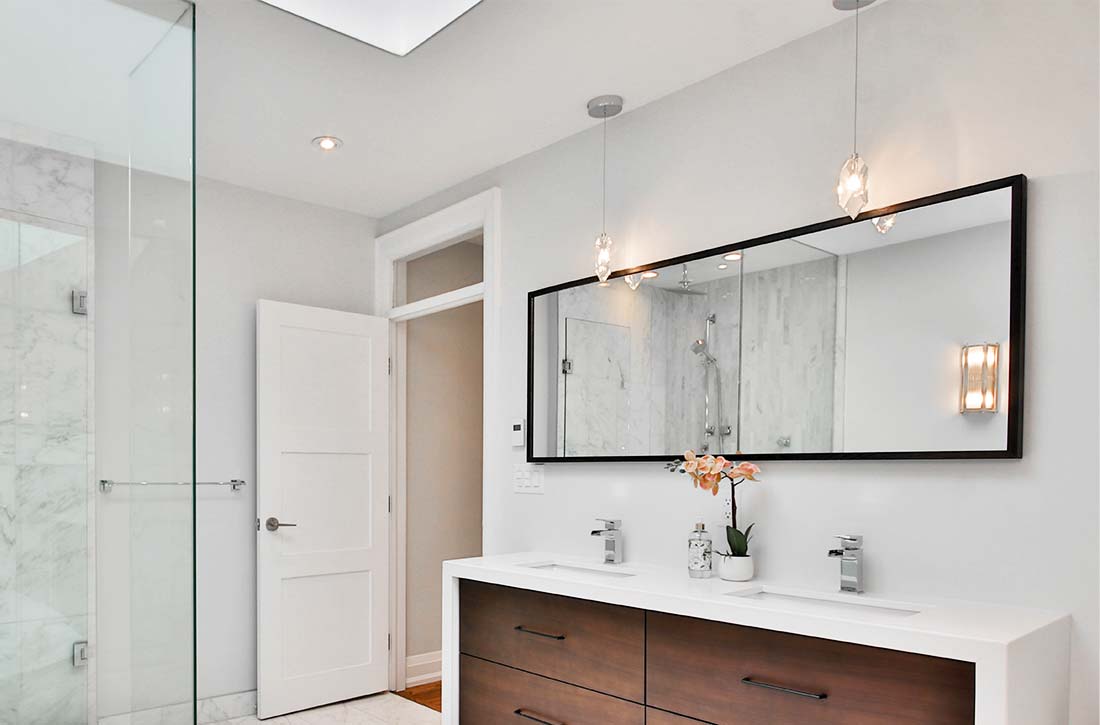 Bathroom with double vanity and two geometric statment pendants.