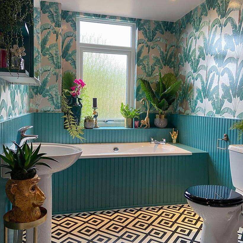 Eclectic bathroom with tropical wallpaper and teal molding.