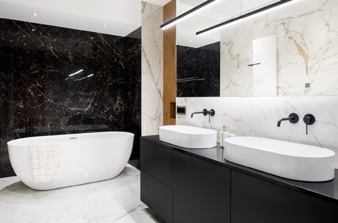 Bathroom with black vanity and black and white marble walls.