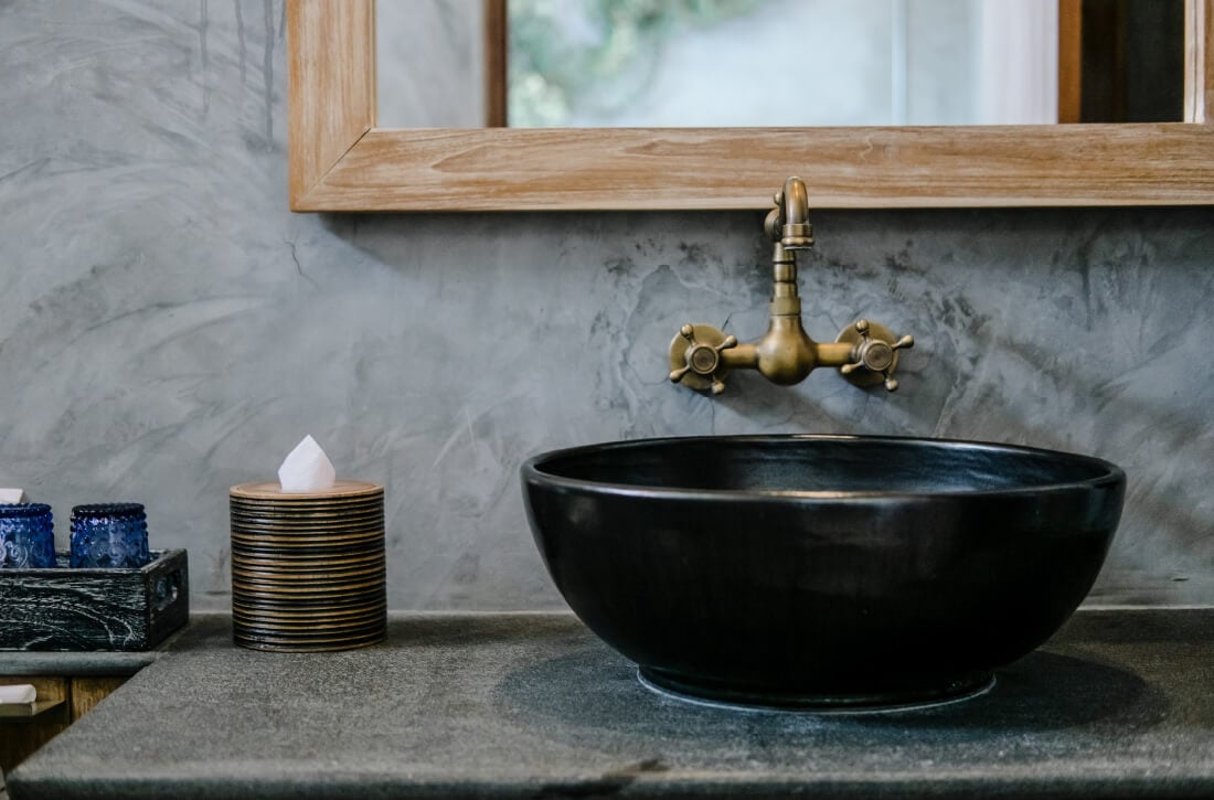 Black bowl bathroom sink with industrial bronze faucet.