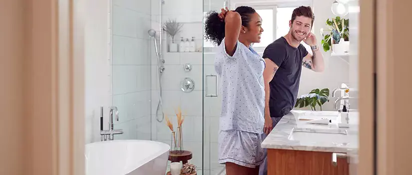 Couple getting ready at bathroom vanity.