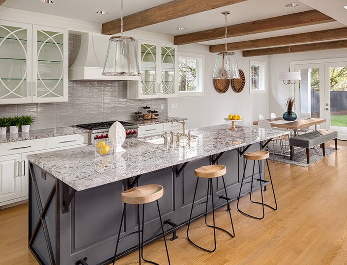 White birch cabinets with speckled gray countertops and a gray island.