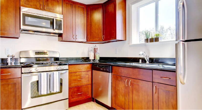 Red-brown cherry wood kitchen with black countertops.