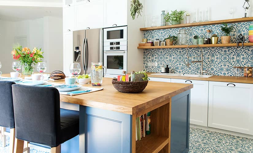 Colorful kitchen with blue kitchen island and blue and green Moroccan tile.
