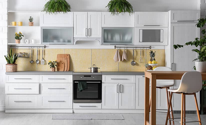 Small galley kitchen with white cabinets and yellow backsplash.