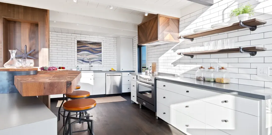 Airy coastal kitchen with a wood island, subway tile backsplash, and industrial grey countertops.