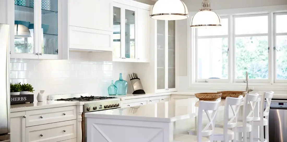 Airy coastal kitchen with white countertops and cabinets and island seating.