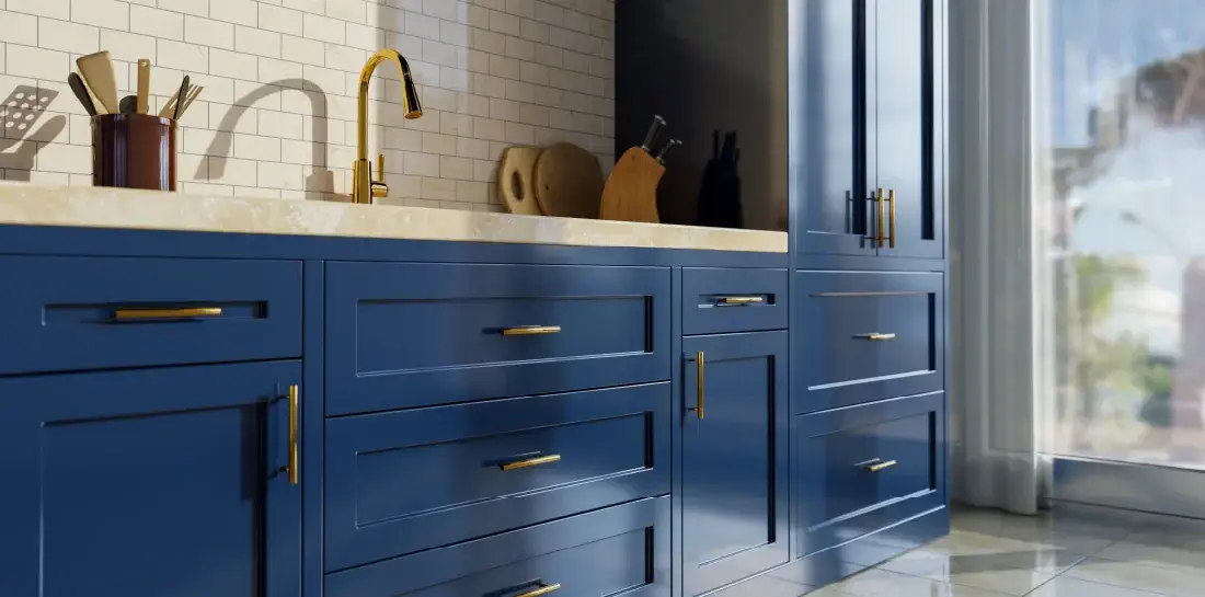 Kitchen sink with navy blue shaker-style cabinets with gold hardware.