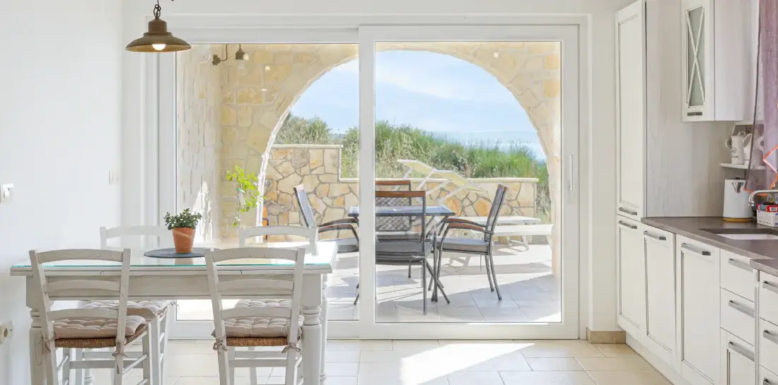 Natural airy coastal kitchen with a sliding door and a view of the ocean.