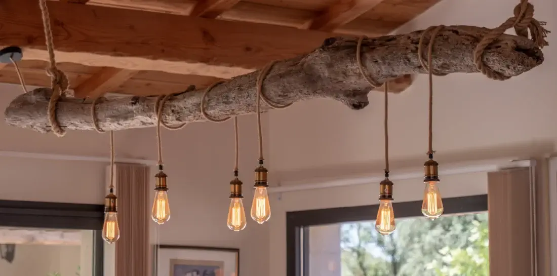 Organic kitchen light fixture made of a hanging tree trunk with six edison bulbs hanging from it.