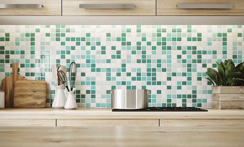 Colorful kitchen backsplash shows a pattern using different shades of green tile.