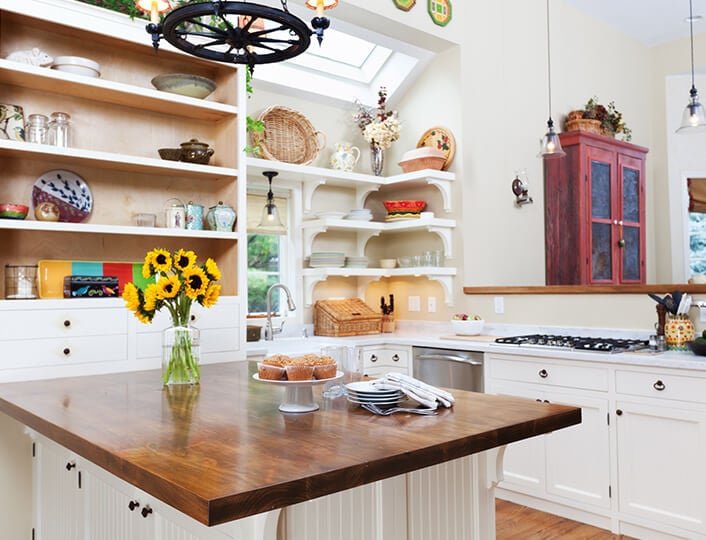 Farmhouse kitchen with warm wood countertops and angled corner drawers.