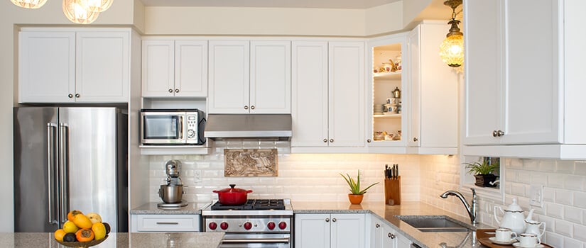 Traditional kitchen with white corner cabinets, silver hardware and granite countertops.