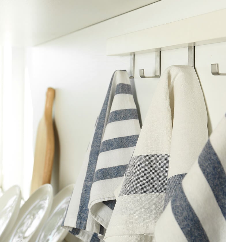 White and silver hanging wall racks under with blue and white stripe kitchen towels.