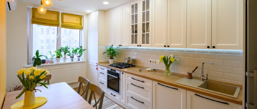 Cozy kitchen with white cabinets, wood countertops, and yellow flowers.