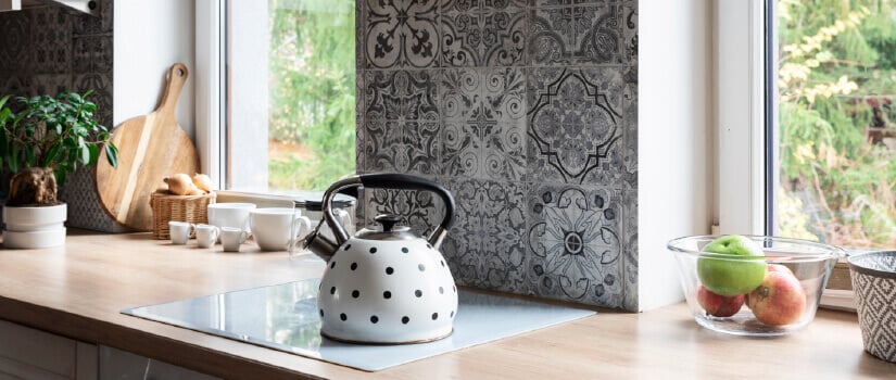Black and white mosaic tile kitchen backsplash against wood countertops.