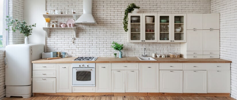 Kitchen with off-white cabinets, wood countertop, and vintage appliances.