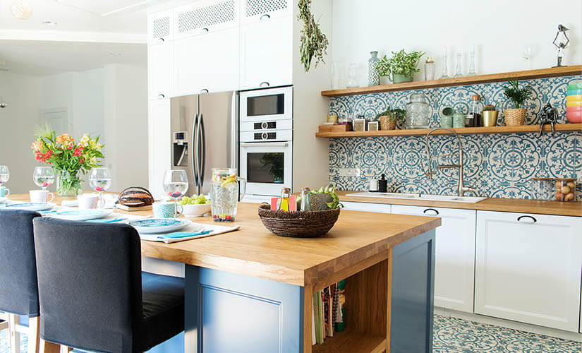 Kitchen with white cabinets, wood countertops, and blue patterned tile backsplash.