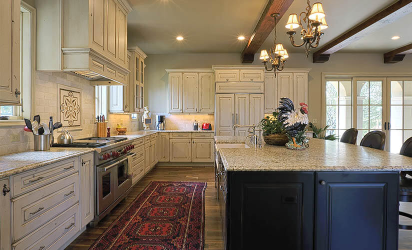 Kitchen with white cabinets and red ornate rug on hardwood floor.