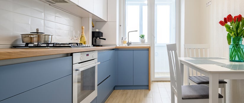 Small kitchen with blue vinyl-wrapped slab cabinets and wood countertops.