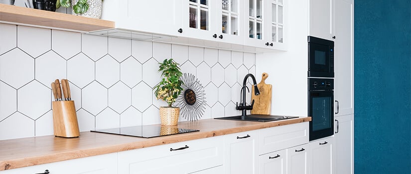 Kitchen with white cabinets, wood countertops, and white hexagon-tile backsplash.