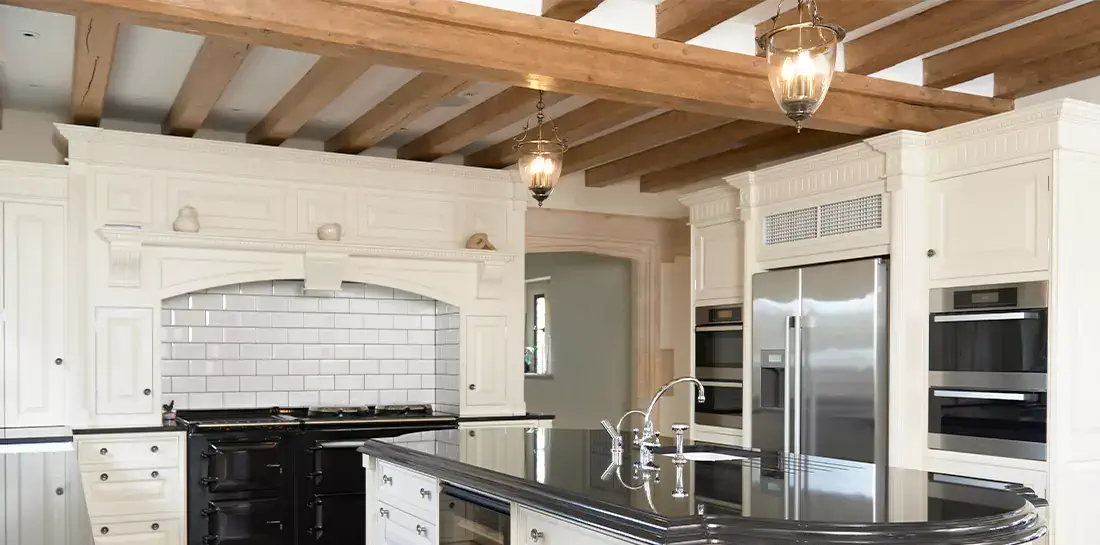 Wood beams on ceiling in a white rustic kitchen.