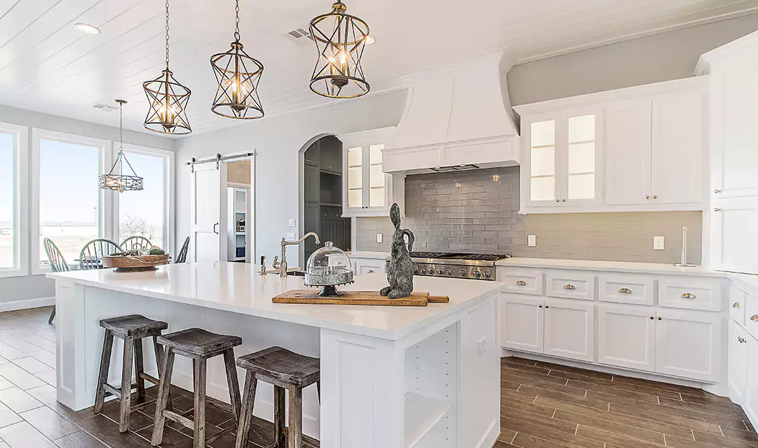 Modern kitchen with white cabinets and cage pendant lights.