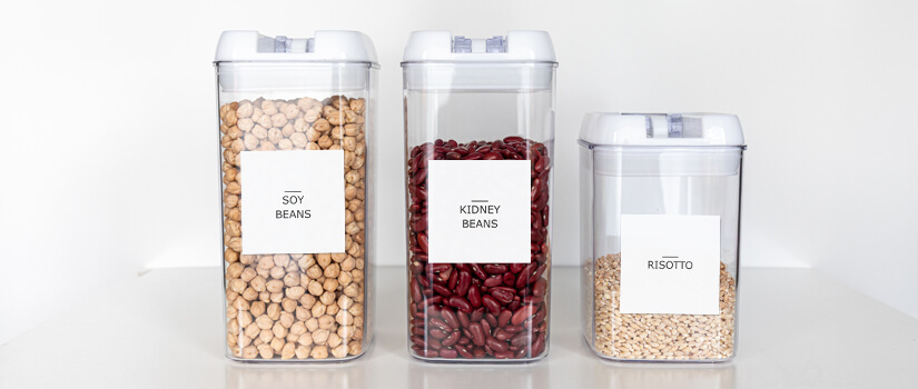 Clear kitchen containers with minimalist food labels on them.