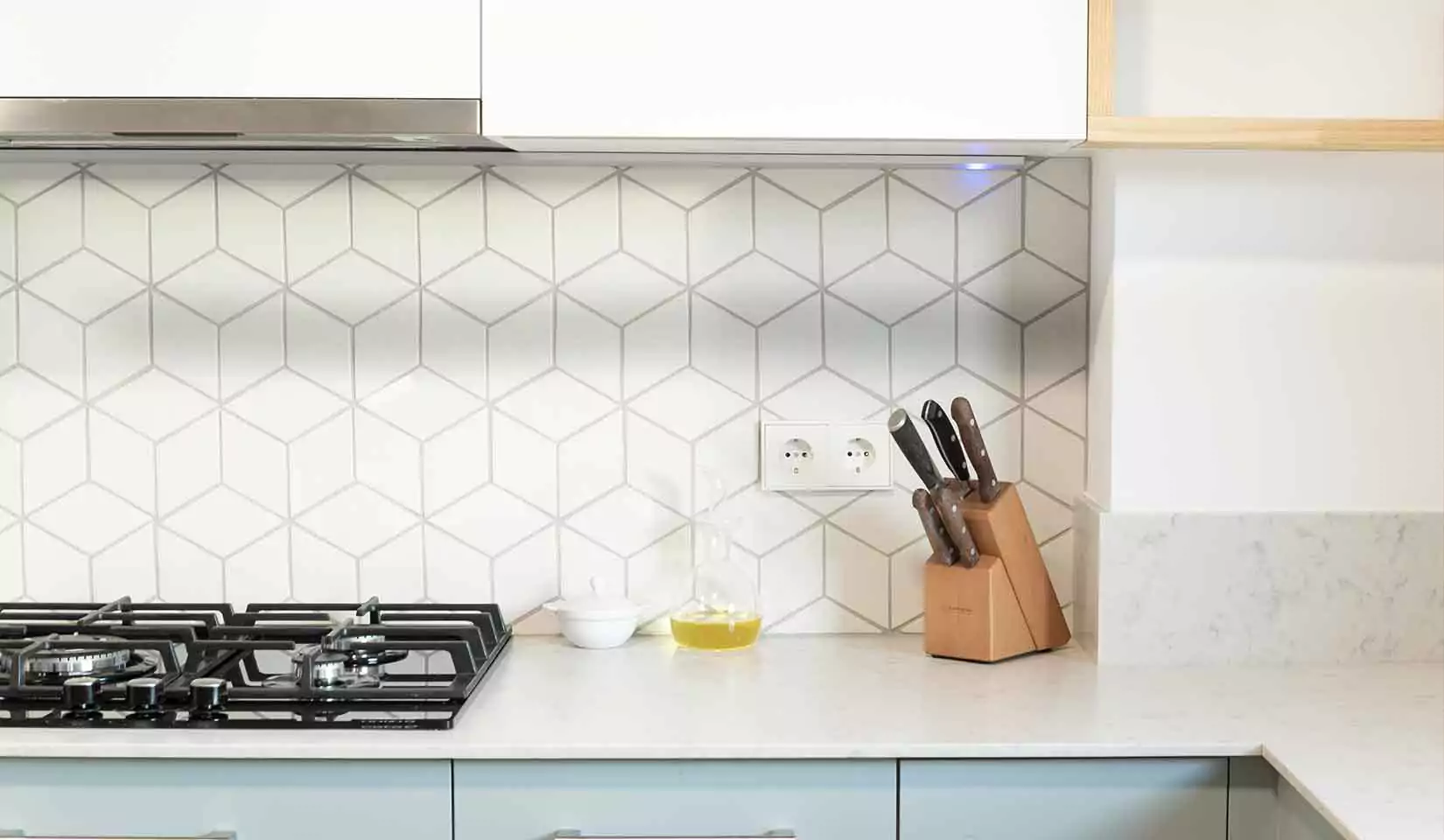 A white tiled backsplash in a light-colored kitchen.