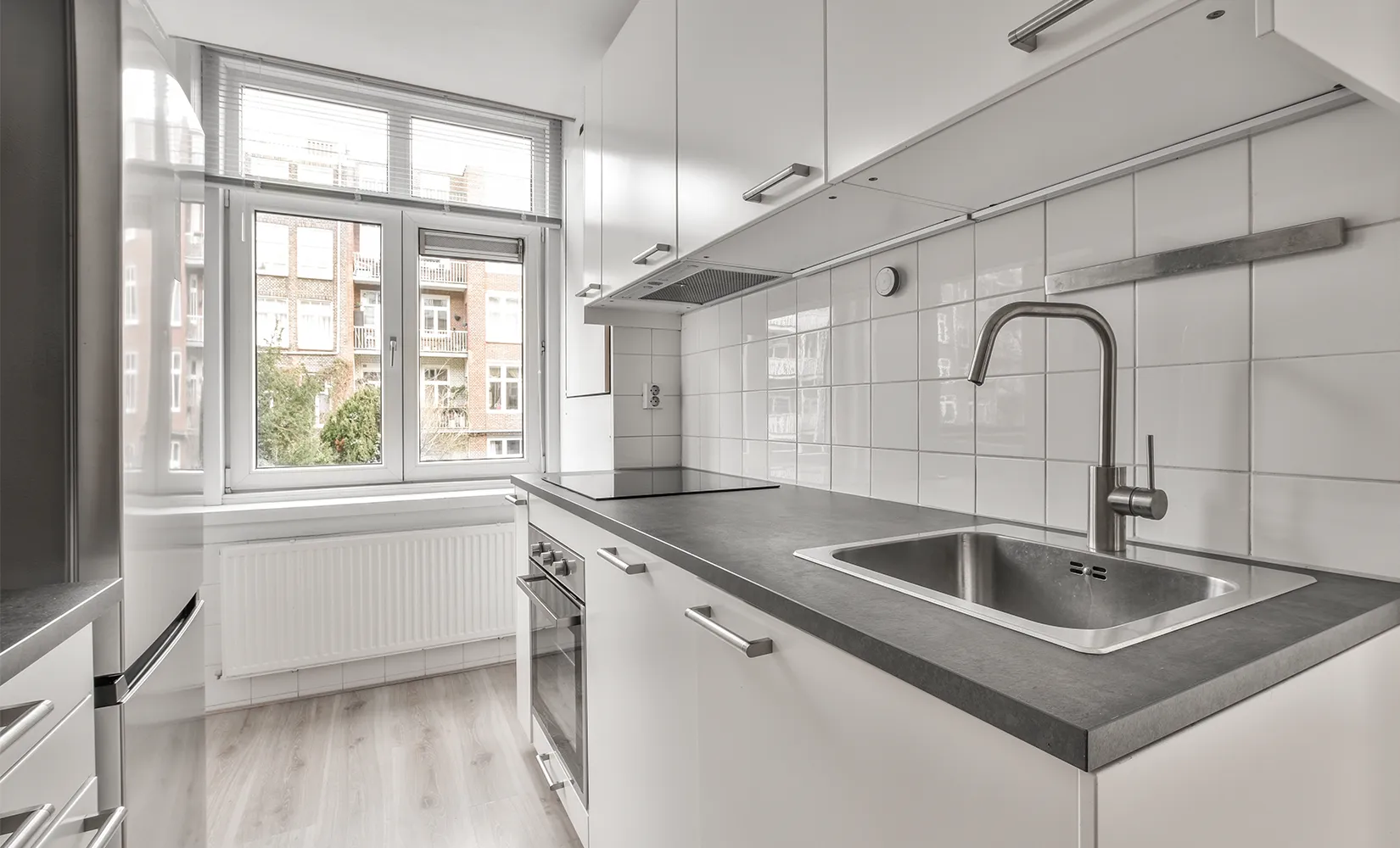 White galley kitchen with sink and stovetop on the same countertop.