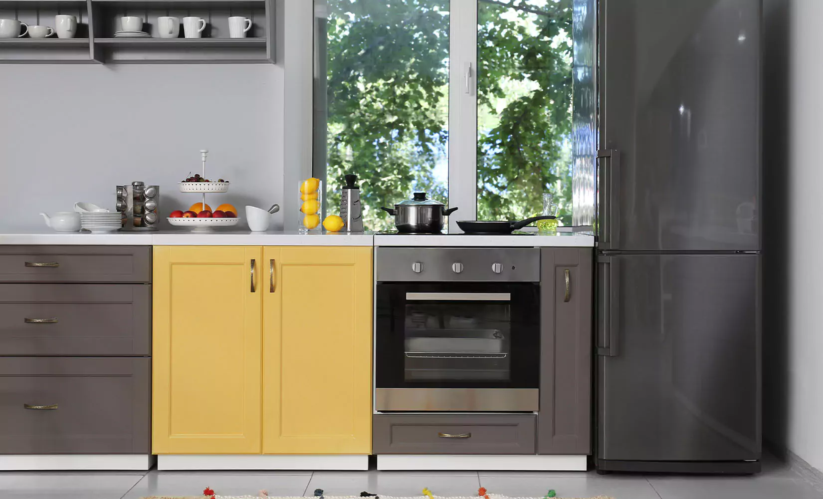 Kitchen with gray cabinets and appliances and one yellow cabinet.