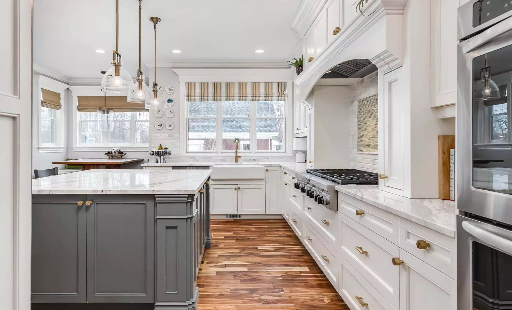 Farmhouse kitchen with gray kitchen island and white surrounding cabinets.