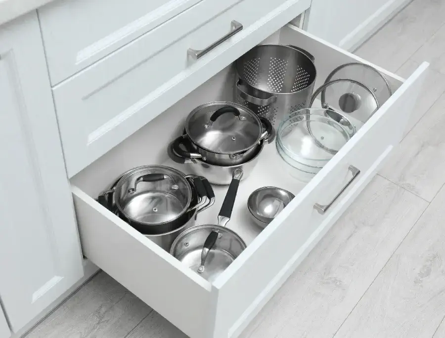 Pots and pans stacked inside a kitchen cabinet.