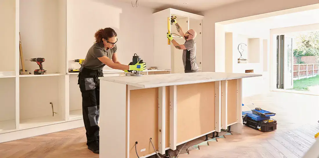 Two people in the process of refinishing kitchen cabinets.