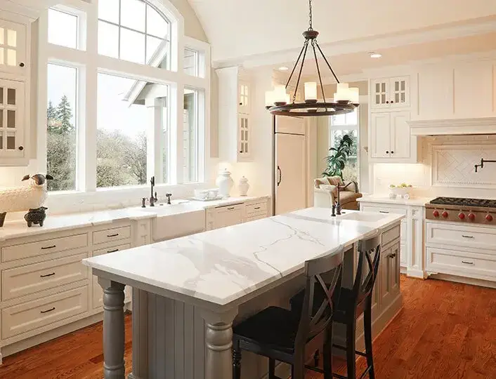 Open concept kitchen with white repainted cabinets and white marble countertops.