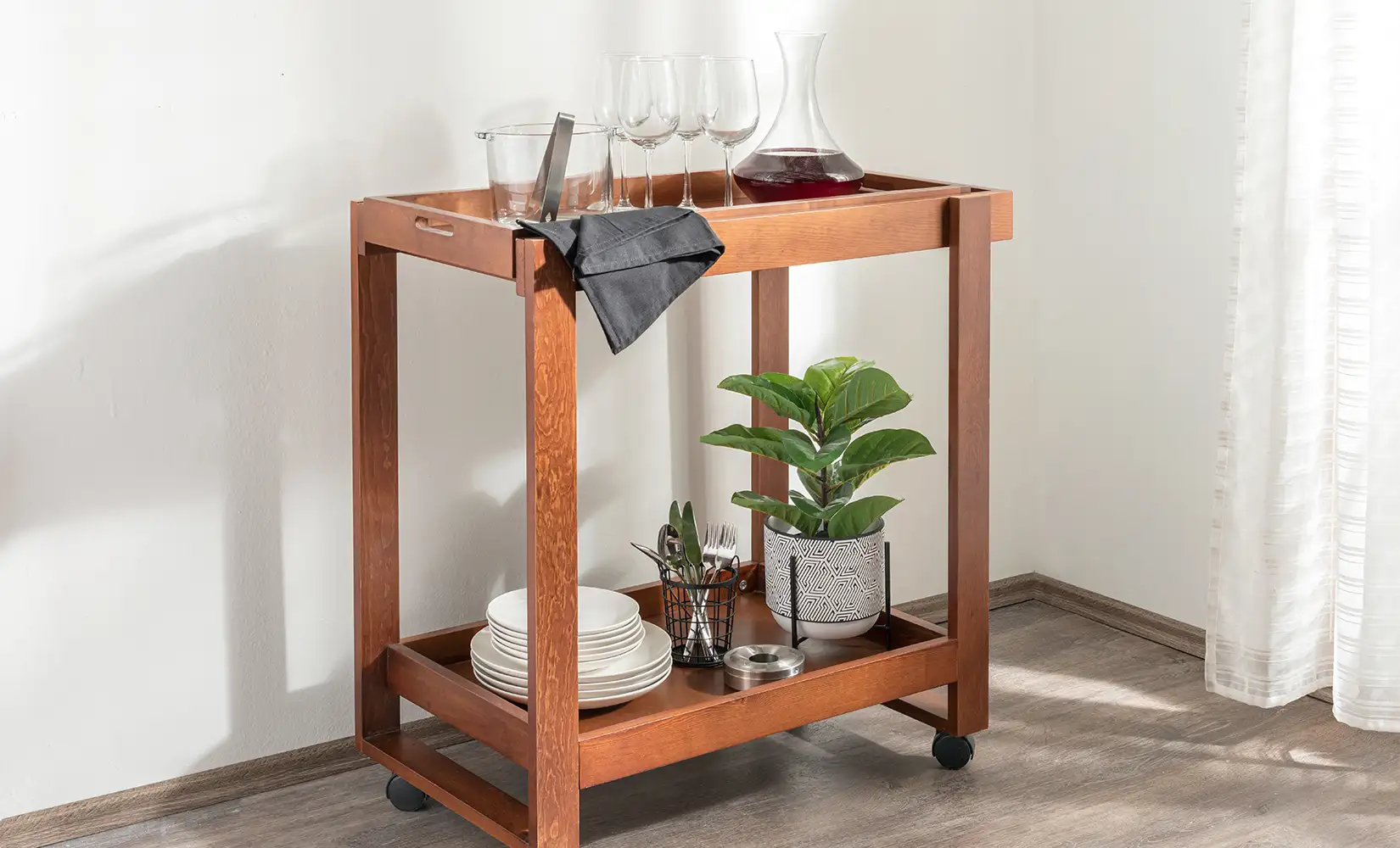Wooden industrial kitchen cart with four wheels carrying dishware.