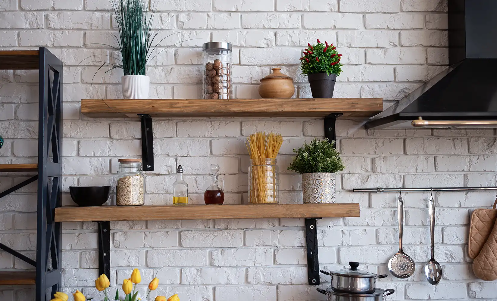Reclaimed wood shelves mounted on white tile backsplash holding kitchen supplies.