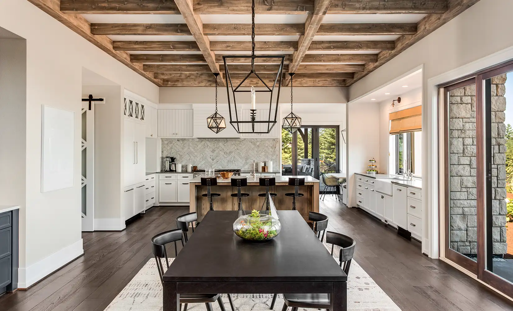 Industrial kitchen with wood ceiling beams, wood flooring, and wooden cabinets in a modern home setting.