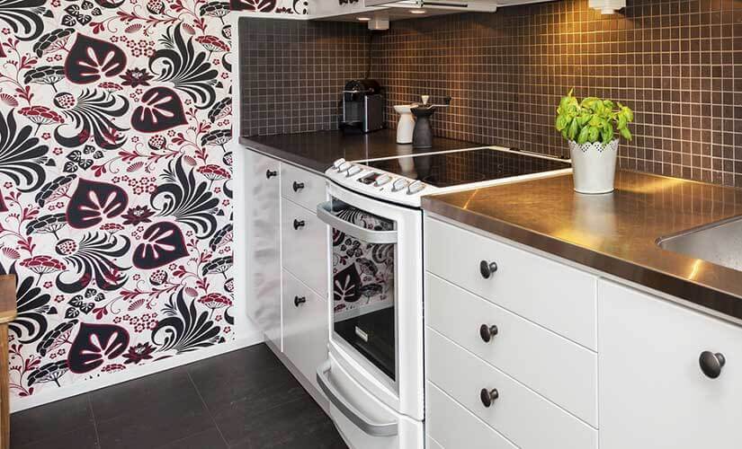 Red, white, black tropical wallpaper with leaves and flowers on kitchen wall