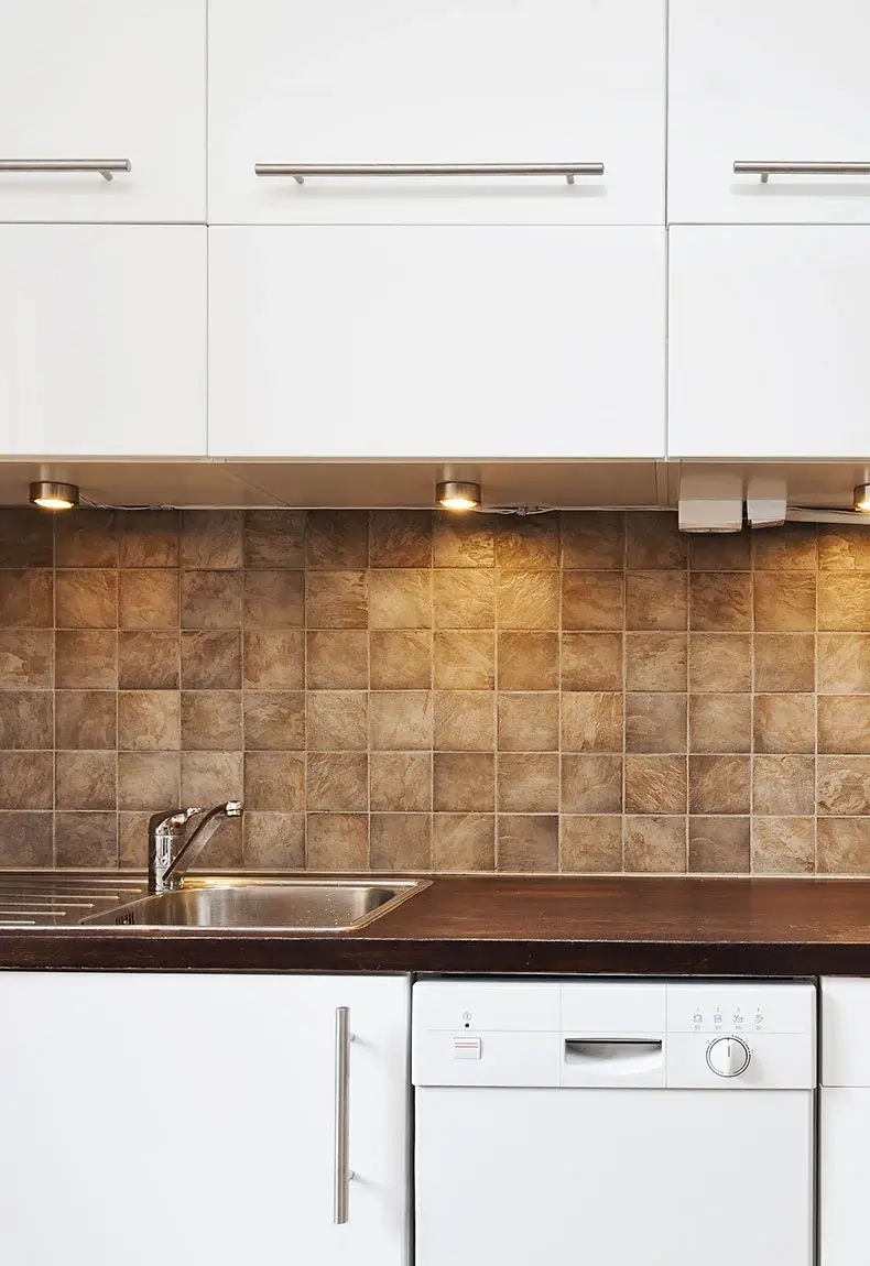 Modern kitchen with white cabinets and rustic brown terracotta tile kitchen backsplash.