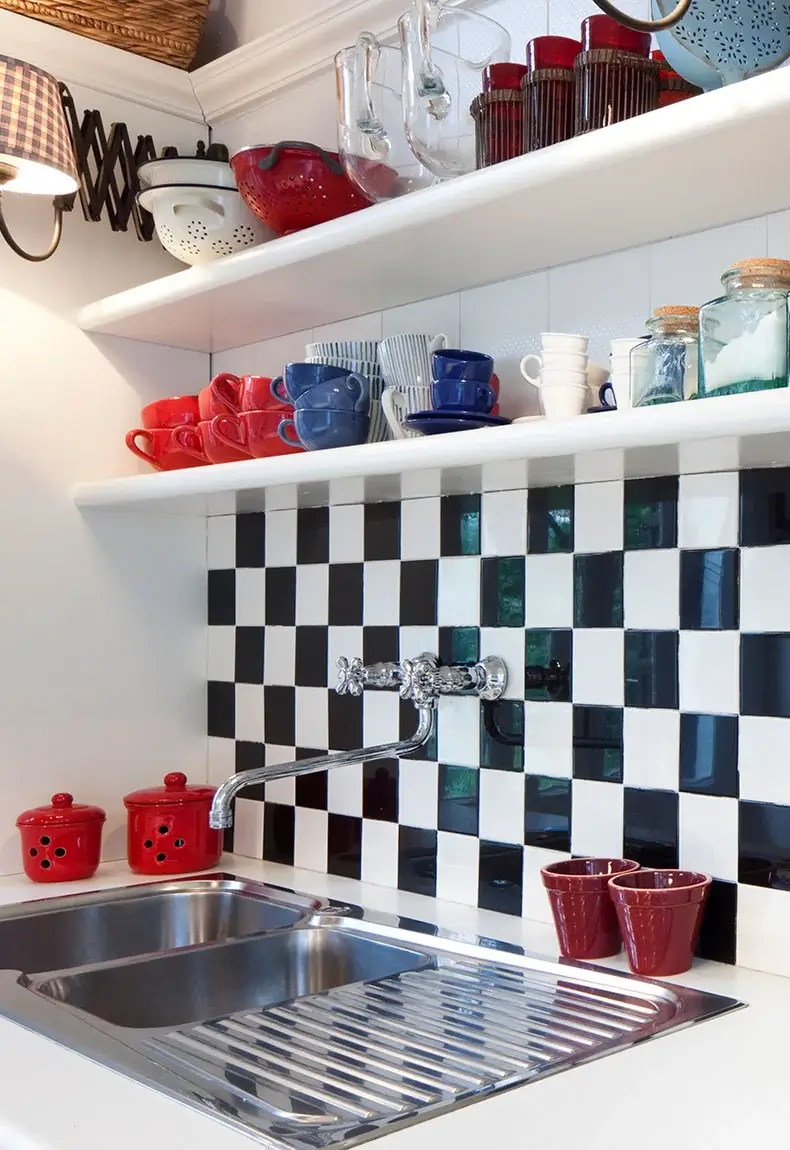 Modern kitchen with black and white checkerboard tiles, shelves, and kitchen accessories.