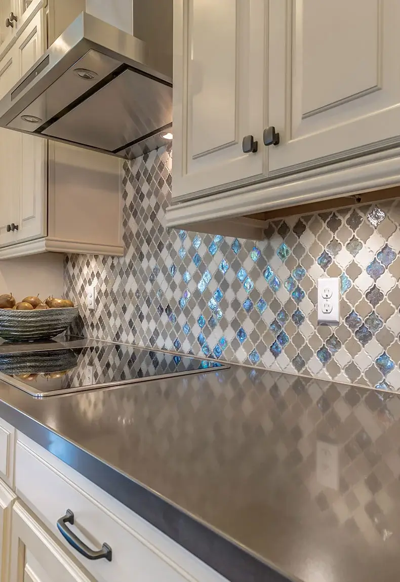 Kitchen interior with gray countertops, white cabinets, kitchen decor, and arabesque mosaic tile backsplash.