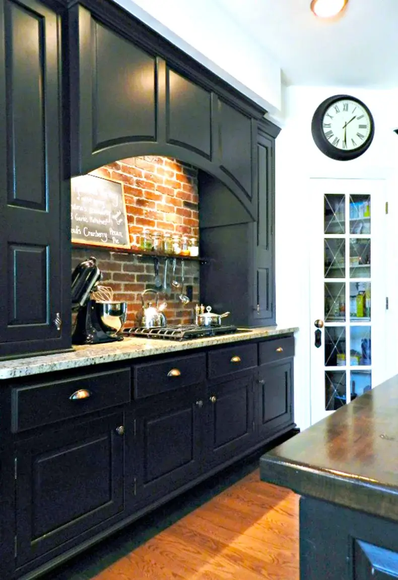 Kitchen with black cabinets and drawers and a brick wall backsplash.