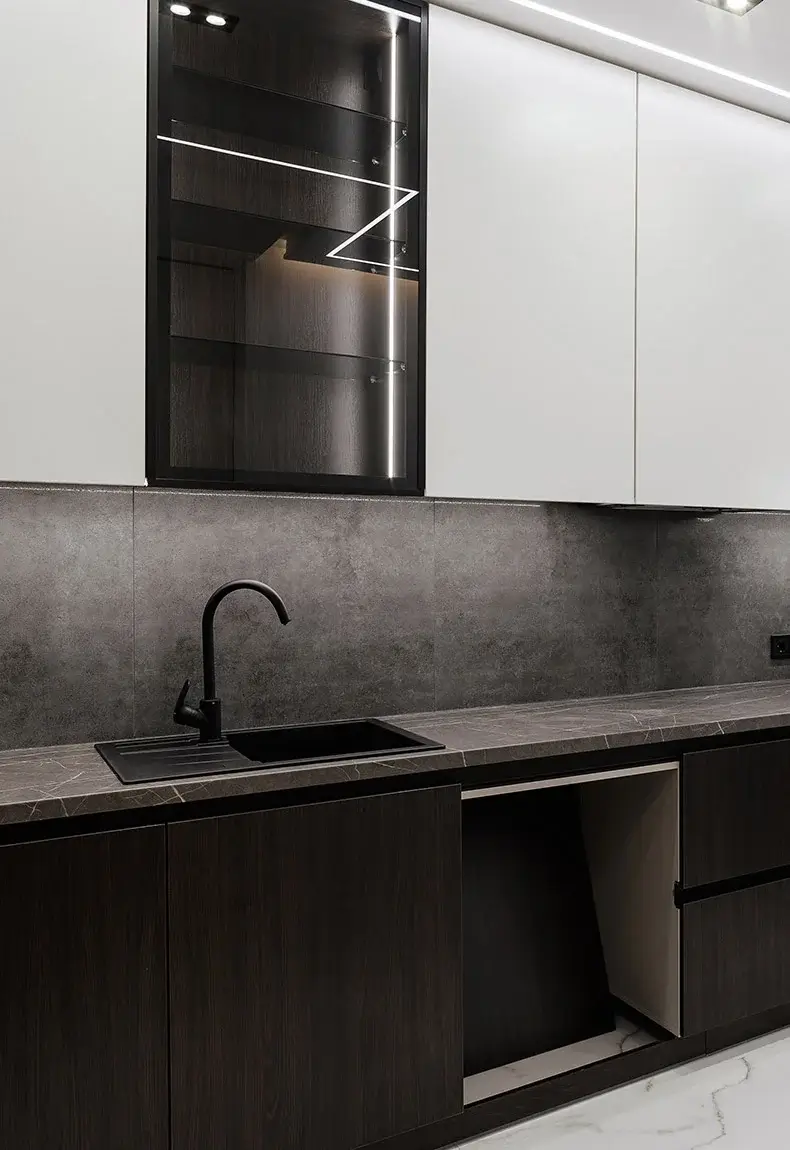 Modern kitchen with dark brown cabinets, gray countertops, white cabinets above sink, and gray soapstone backsplash.