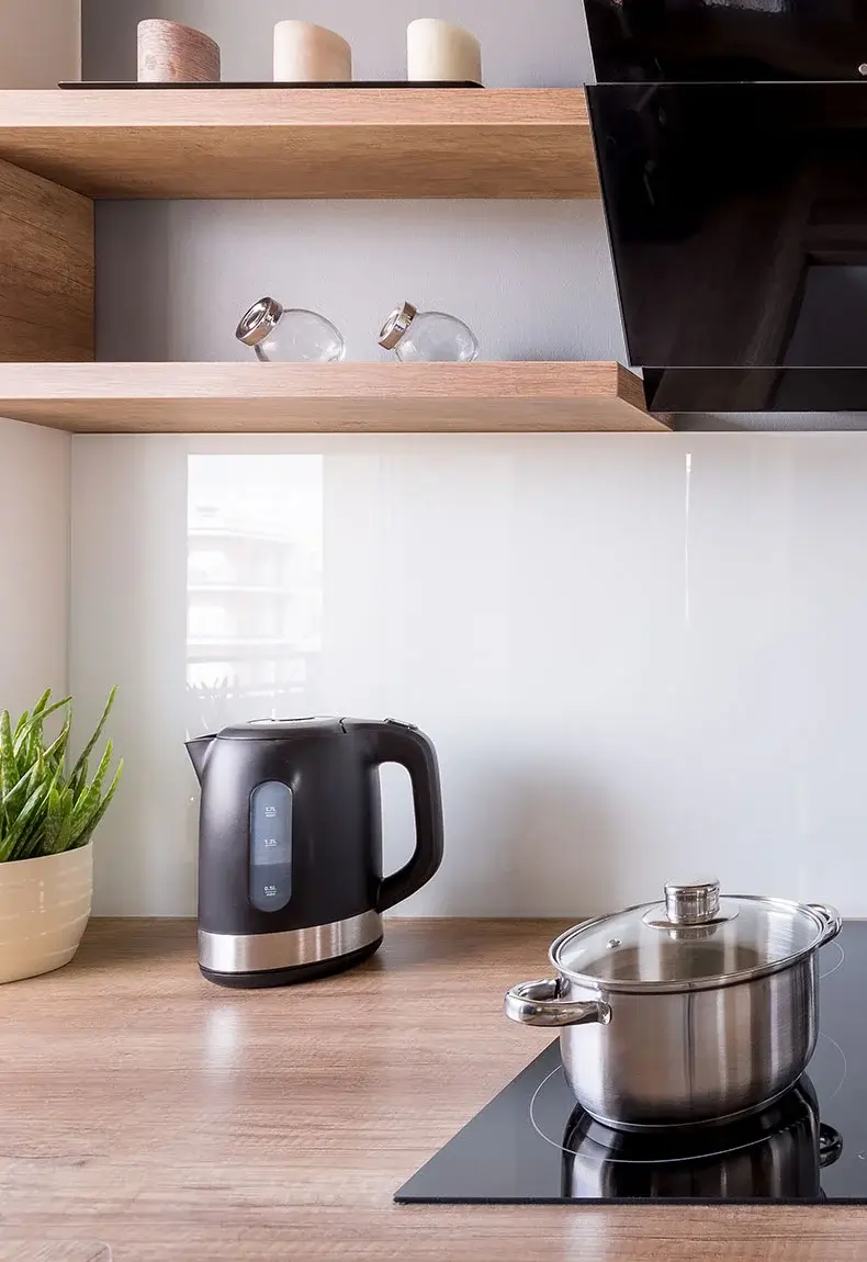 Modern kitchen white white glass backsplash, light brown countertops, and kitchen appliances.