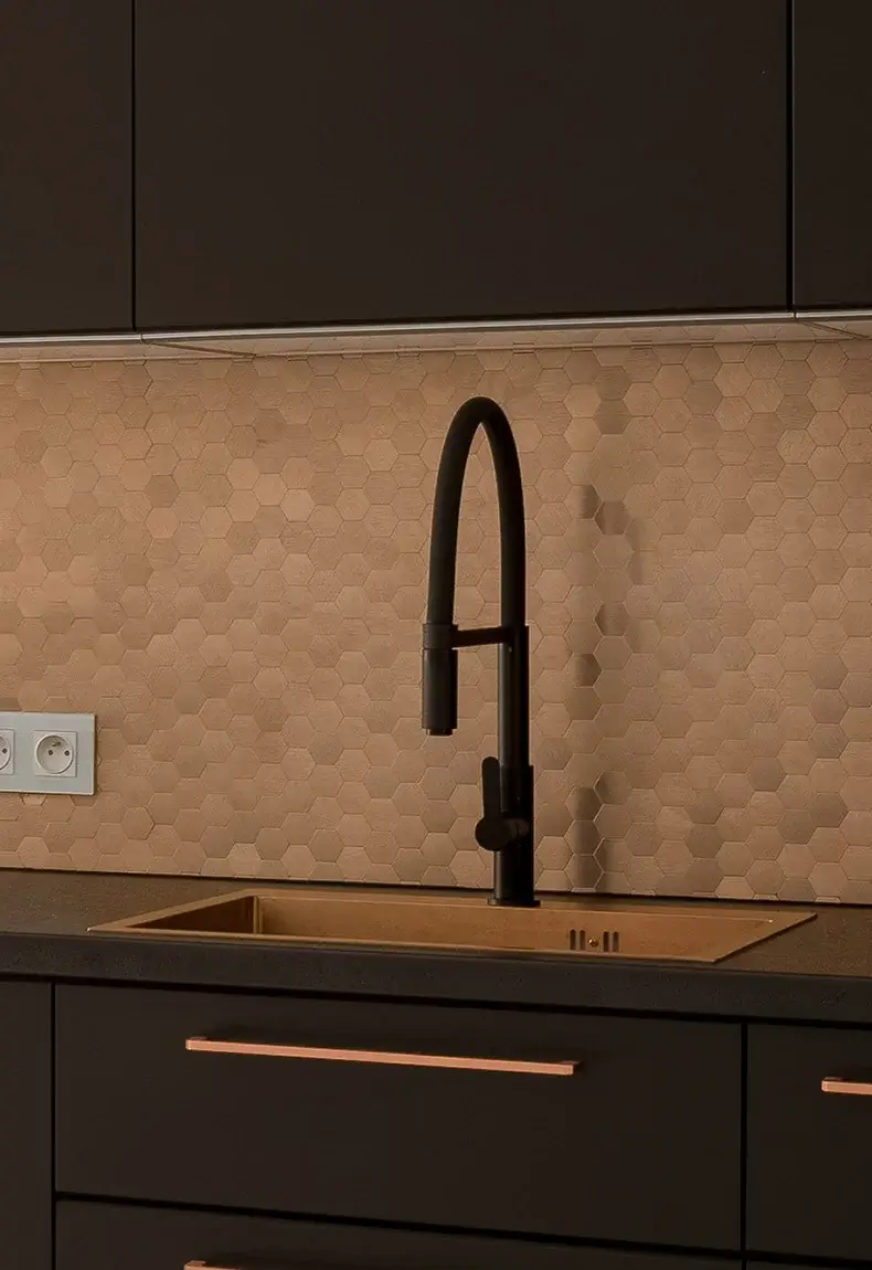 Kitchen with brown cabinets and countertops accented with a light brown hexagon patterned copper backsplash.