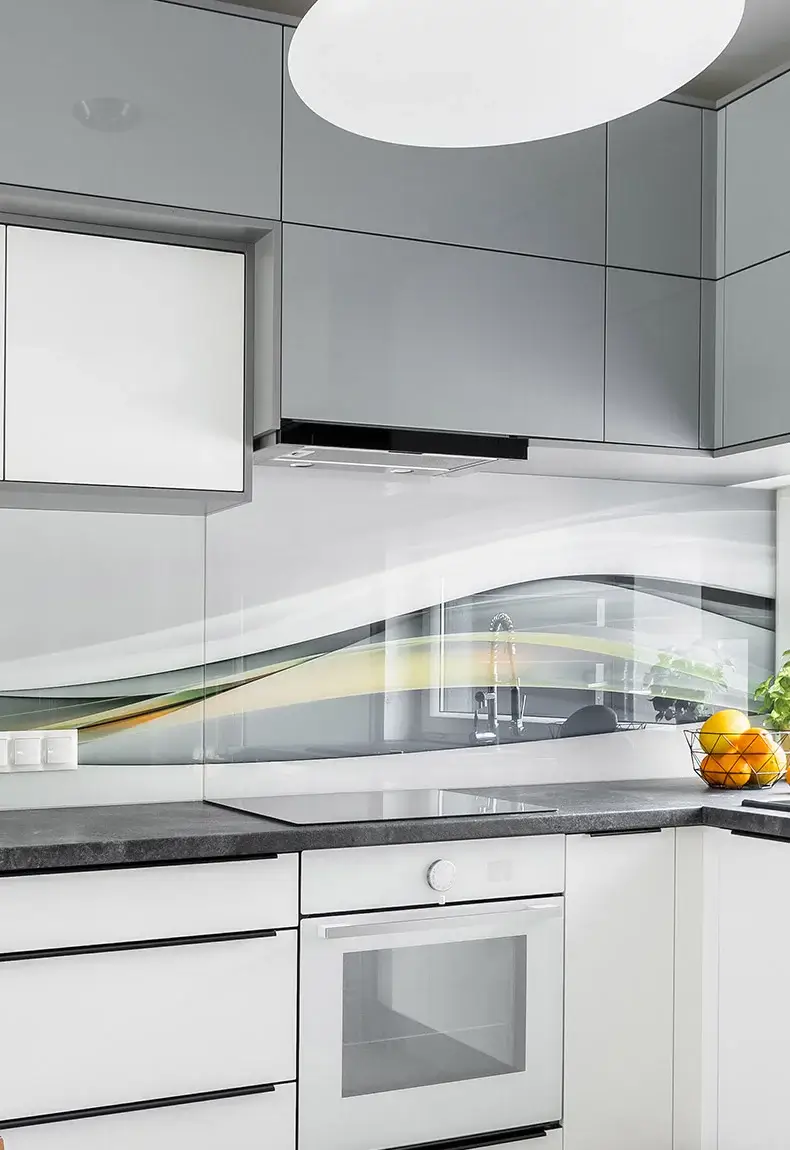 Modern white kitchen with gray cabinets and countertops and shiny mural backsplash with swirling color accents.