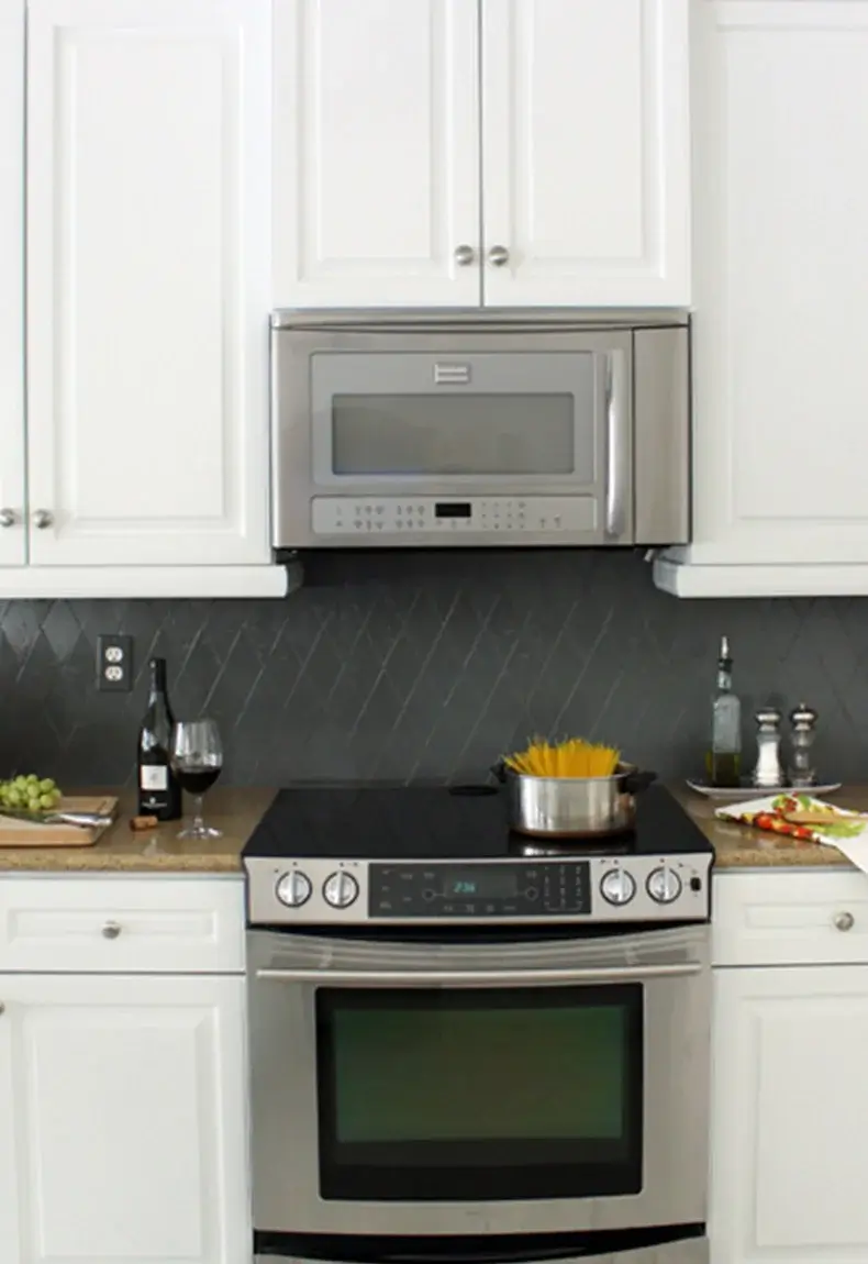 Kitchen with white cabinets and gray diamond pattern backsplash.